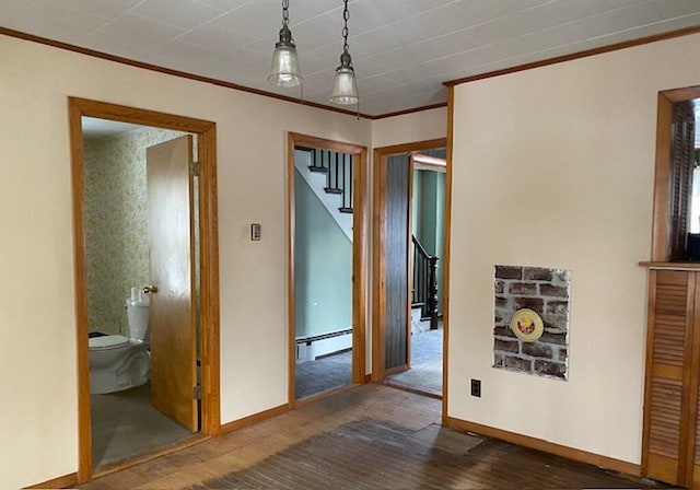 corridor with a baseboard radiator, ornamental molding, and dark hardwood / wood-style flooring