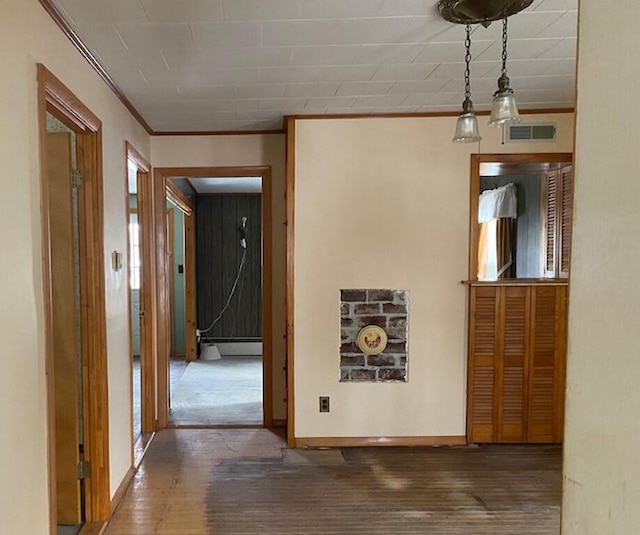 corridor with crown molding, hardwood / wood-style floors, and a baseboard heating unit