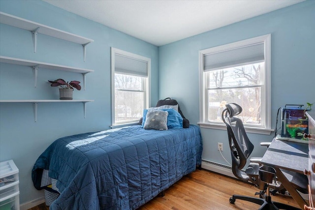 bedroom with a baseboard heating unit and wood-type flooring