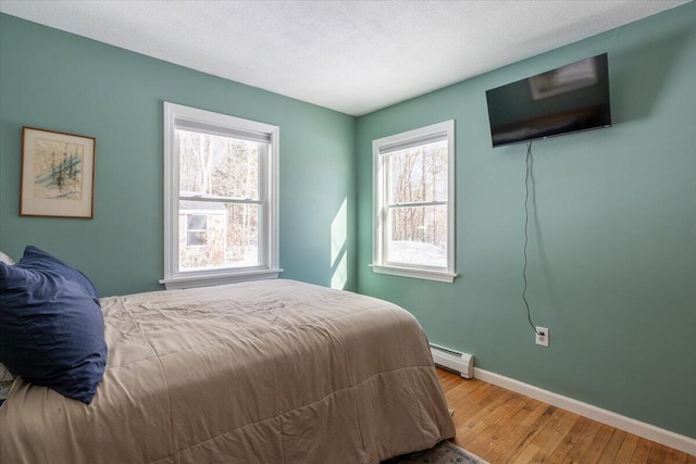 bedroom featuring hardwood / wood-style flooring, a baseboard radiator, and a textured ceiling