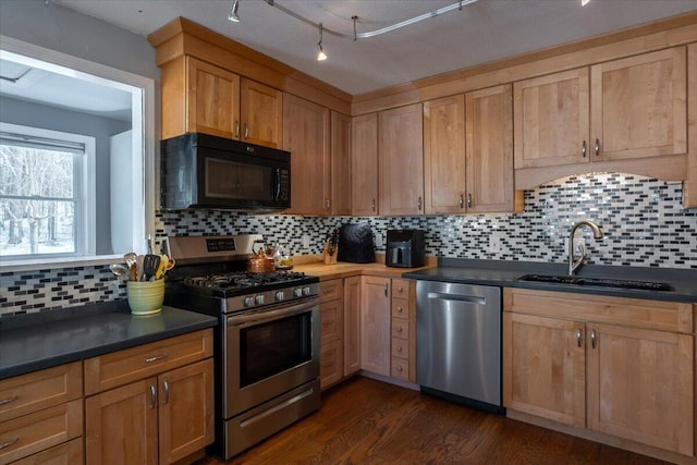 kitchen with tasteful backsplash, appliances with stainless steel finishes, dark hardwood / wood-style flooring, and sink