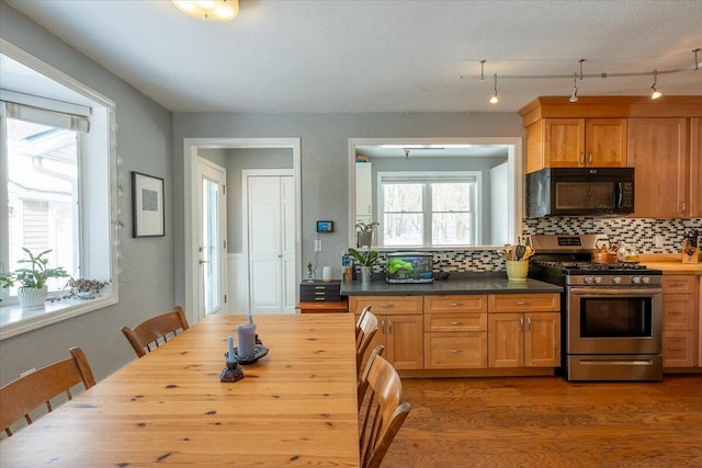 kitchen featuring hardwood / wood-style floors, decorative backsplash, gas stove, and a textured ceiling