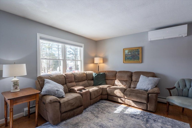 living room featuring baseboard heating, hardwood / wood-style floors, a wall unit AC, and a textured ceiling