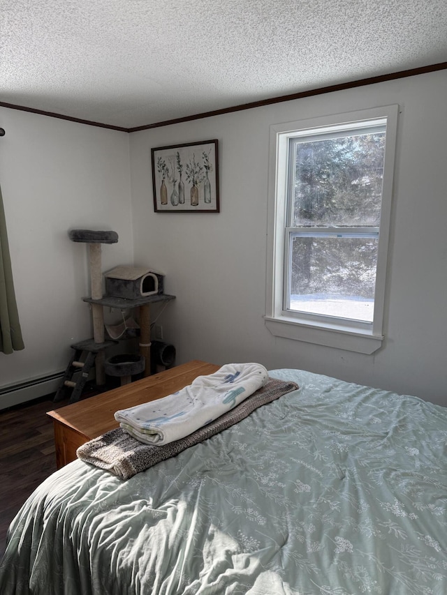 bedroom with crown molding, dark hardwood / wood-style floors, a textured ceiling, and a baseboard heating unit