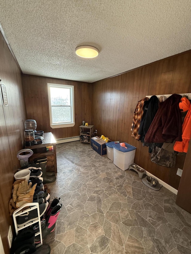 misc room featuring a baseboard radiator, a textured ceiling, and wood walls