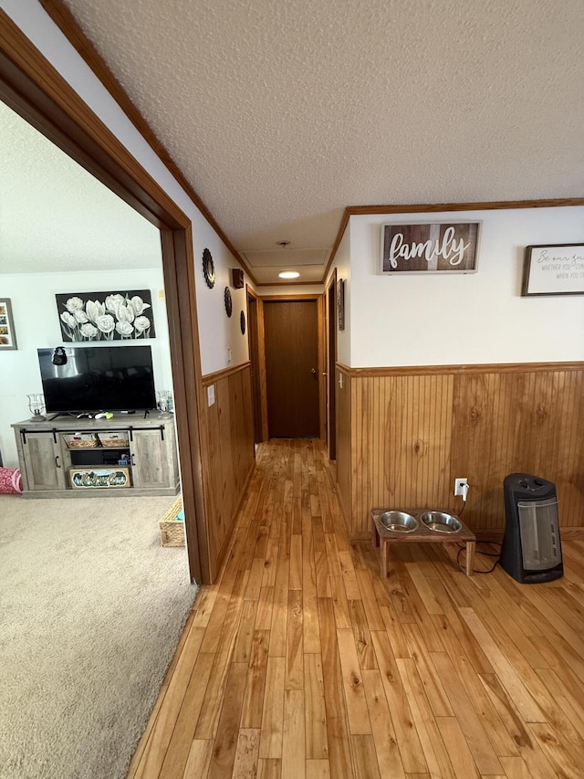 hall featuring crown molding, light hardwood / wood-style floors, and a textured ceiling