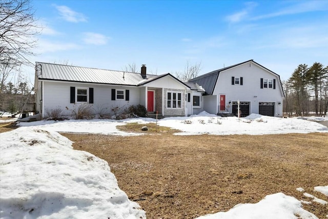 view of front of property featuring a garage, a chimney, a gambrel roof, and metal roof