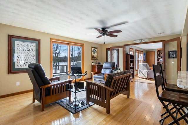 living room featuring light wood-style flooring, baseboards, and ceiling fan