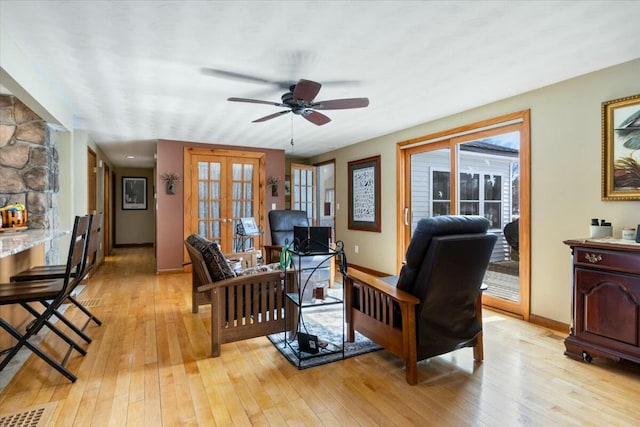 living room featuring french doors, baseboards, light wood finished floors, and ceiling fan