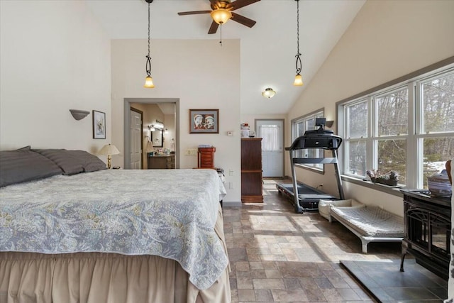 bedroom with high vaulted ceiling, stone finish flooring, and a wood stove