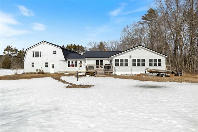 snow covered house featuring a deck, a gambrel roof, and metal roof