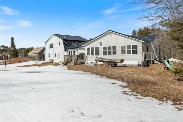 snow covered house featuring metal roof