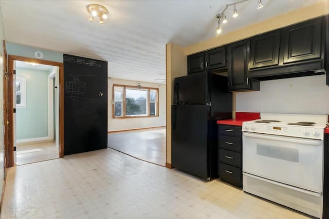 kitchen featuring under cabinet range hood, light floors, freestanding refrigerator, white electric range, and dark cabinets