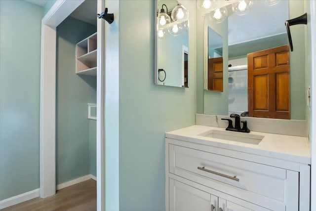 bathroom featuring baseboards, wood finished floors, and vanity