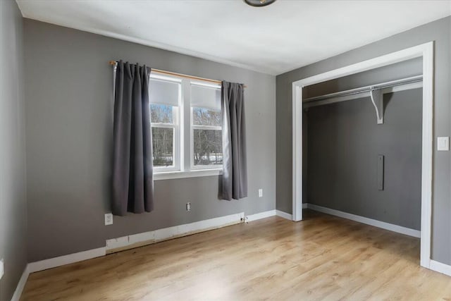 unfurnished bedroom with wood finished floors, baseboards, and a closet