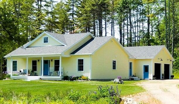 view of front of house featuring a garage, covered porch, and a front yard