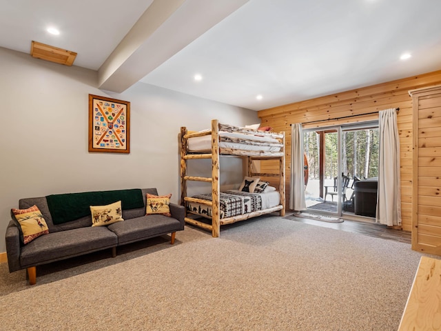 carpeted bedroom featuring access to exterior and wooden walls