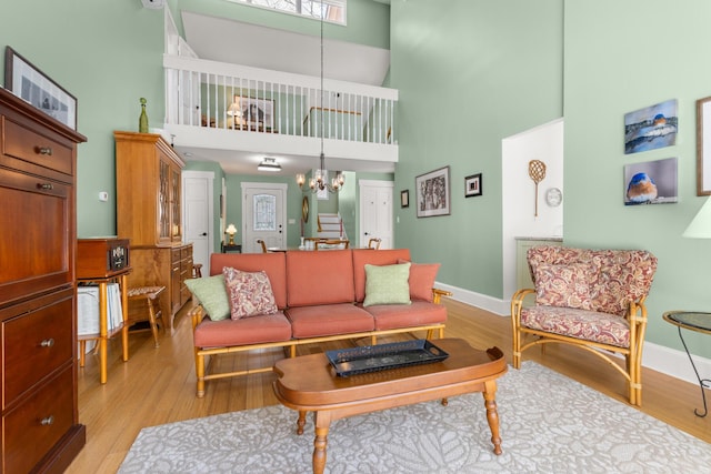 living room featuring a towering ceiling, light hardwood / wood-style floors, and a notable chandelier