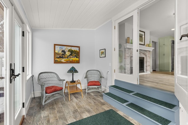 sitting room with wood ceiling, ornamental molding, wood-type flooring, and a fireplace