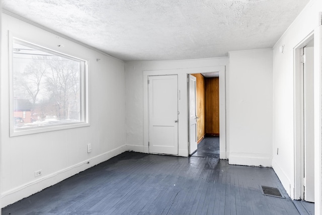 spare room featuring dark hardwood / wood-style floors and a textured ceiling