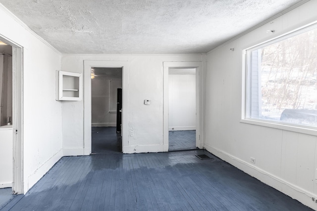 unfurnished bedroom featuring dark wood-type flooring, ornamental molding, and a textured ceiling