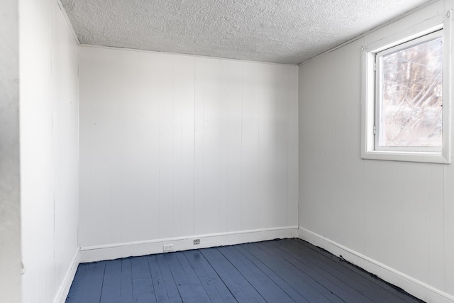 empty room with wood-type flooring and a textured ceiling