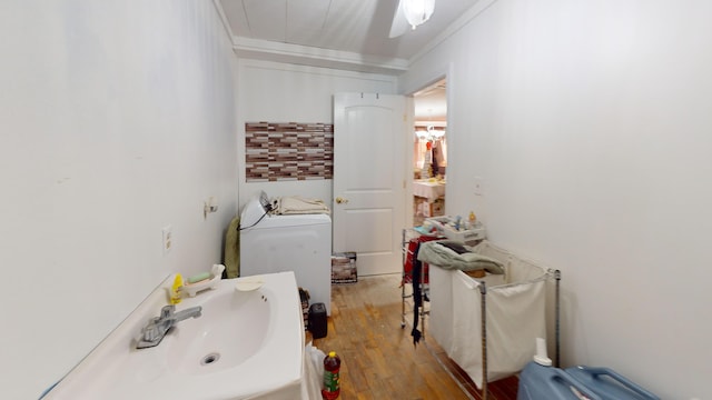 bathroom with ornamental molding, washer / dryer, a sink, and wood finished floors