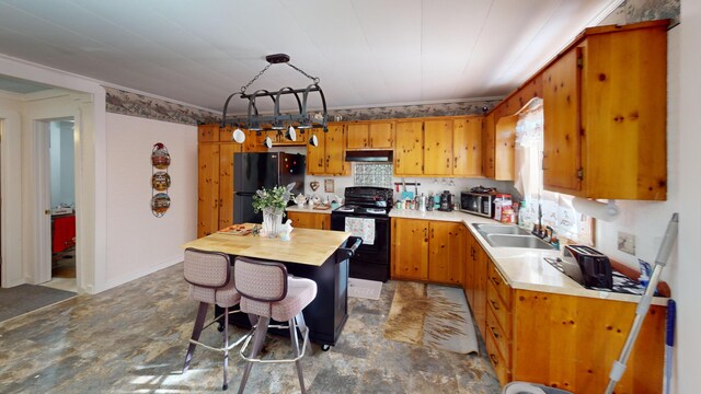 kitchen with brown cabinets, light countertops, under cabinet range hood, and black appliances