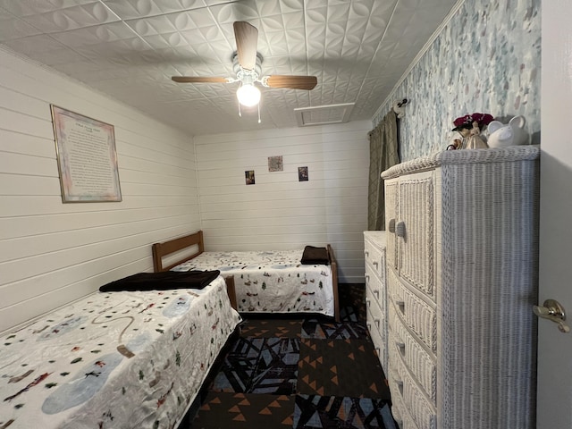 bedroom featuring crown molding, wood walls, attic access, and a ceiling fan