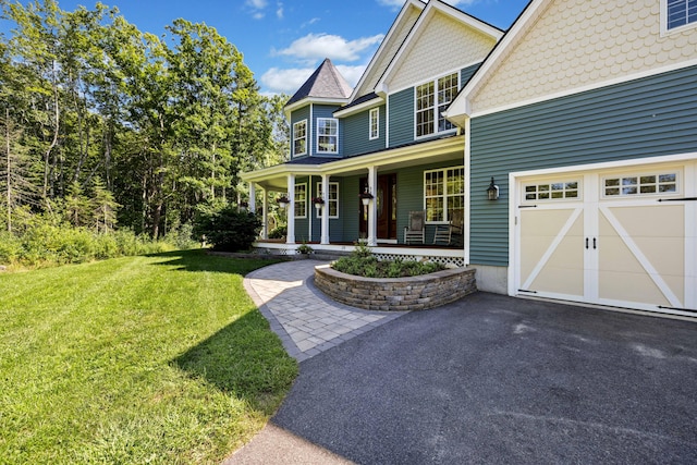 view of front of home featuring a garage, a front yard, and a porch