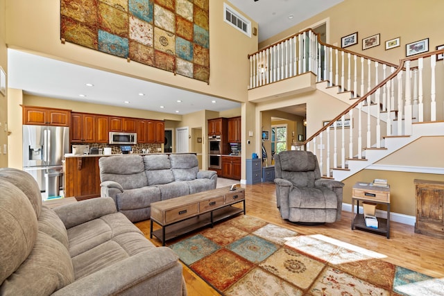 living room featuring a towering ceiling and light hardwood / wood-style floors