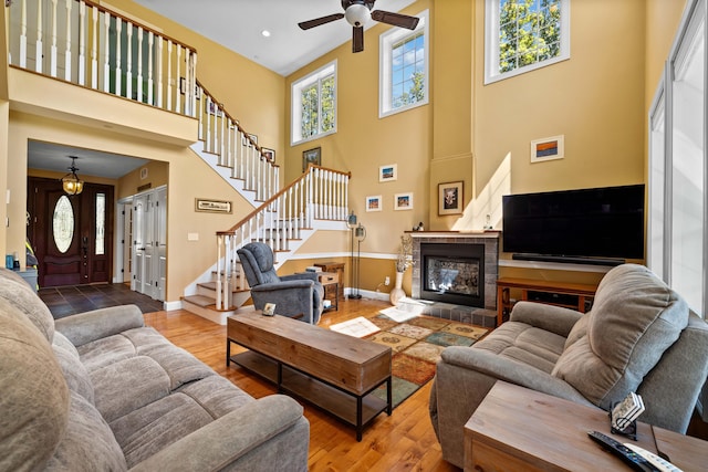 living room with ceiling fan, a towering ceiling, and hardwood / wood-style floors