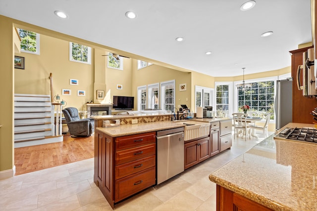 kitchen featuring appliances with stainless steel finishes, sink, hanging light fixtures, a large island with sink, and light stone countertops