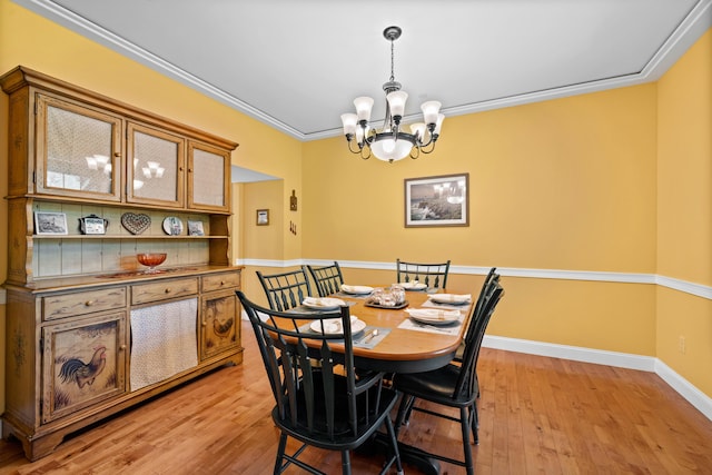 dining area with crown molding, a notable chandelier, and light hardwood / wood-style flooring