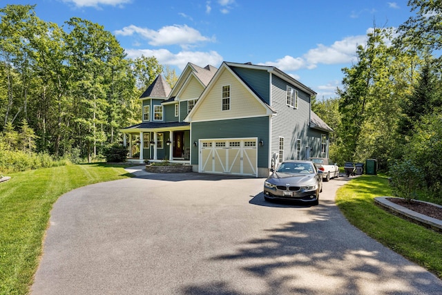 view of front of home featuring a garage, covered porch, and a front yard