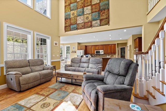 living room with a towering ceiling and light hardwood / wood-style floors