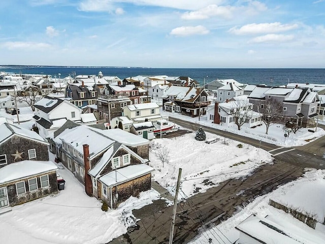 snowy aerial view with a water view and a residential view