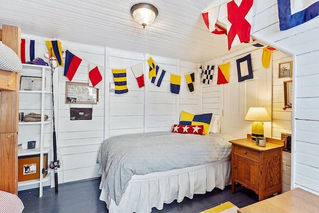 bedroom with wood walls and wood finished floors