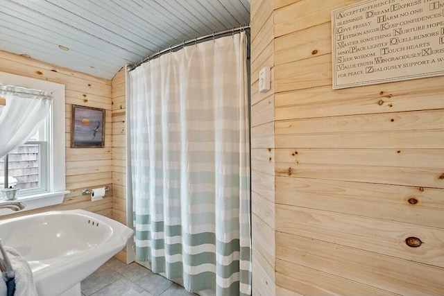 full bath with wood walls, tile patterned flooring, a sink, and a shower with shower curtain