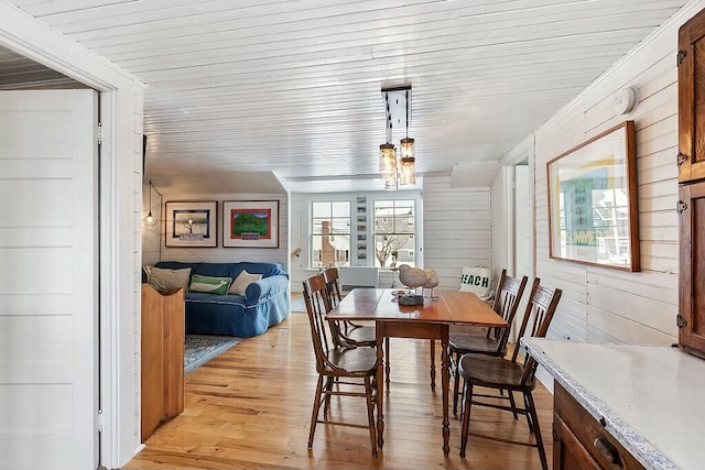 dining space with wooden ceiling, wood walls, and light wood finished floors