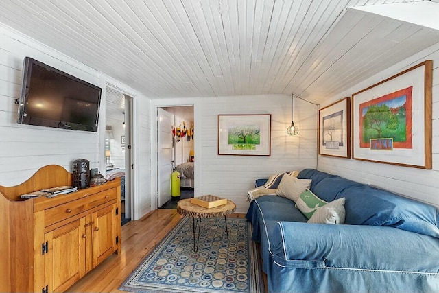 living room with lofted ceiling, light wood-type flooring, wooden ceiling, and wooden walls