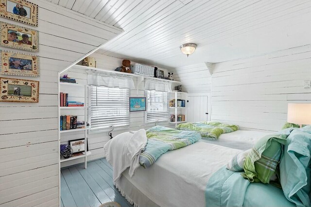 bedroom with wooden ceiling, wooden walls, and wood finished floors