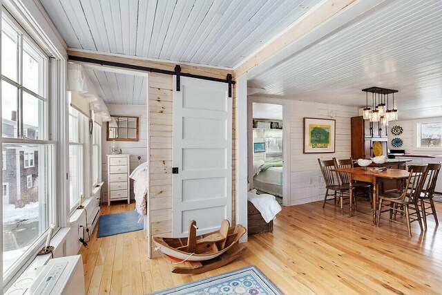 interior space with a chandelier, a barn door, wood ceiling, and a healthy amount of sunlight