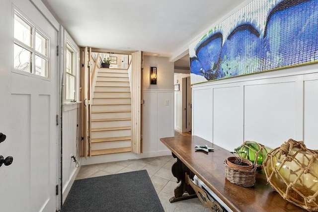 interior space featuring a wainscoted wall, light tile patterned flooring, and a decorative wall