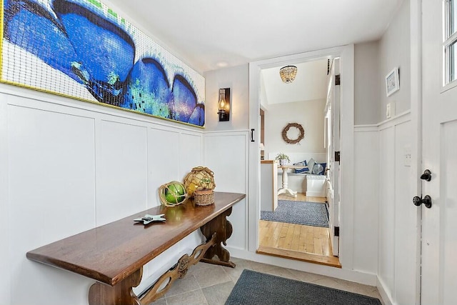 mudroom with a wainscoted wall, a decorative wall, and tile patterned floors