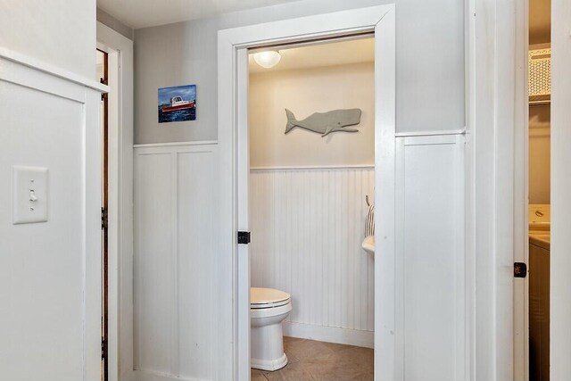 bathroom featuring toilet and a wainscoted wall