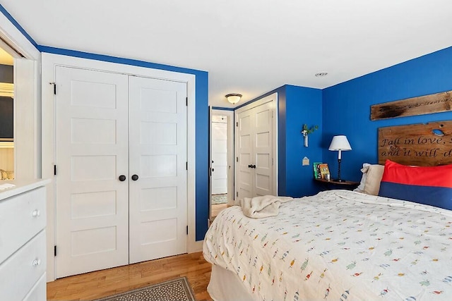 bedroom featuring wood finished floors and multiple closets