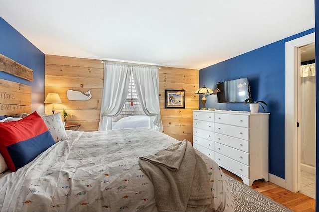 bedroom with wood walls, an accent wall, and wood finished floors