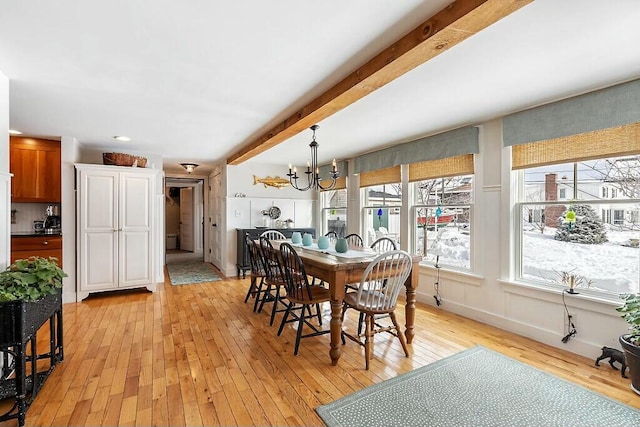 dining room featuring light wood-style floors, beam ceiling, baseboards, and an inviting chandelier