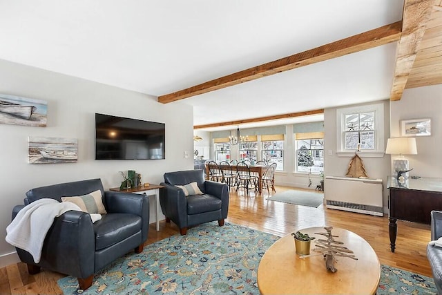 living room with beamed ceiling, an inviting chandelier, and wood finished floors